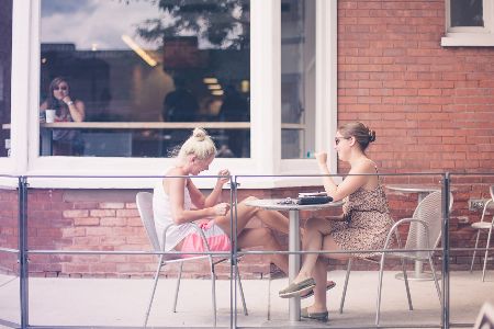 Two women sitting outside a restaurant laughing and smiling.